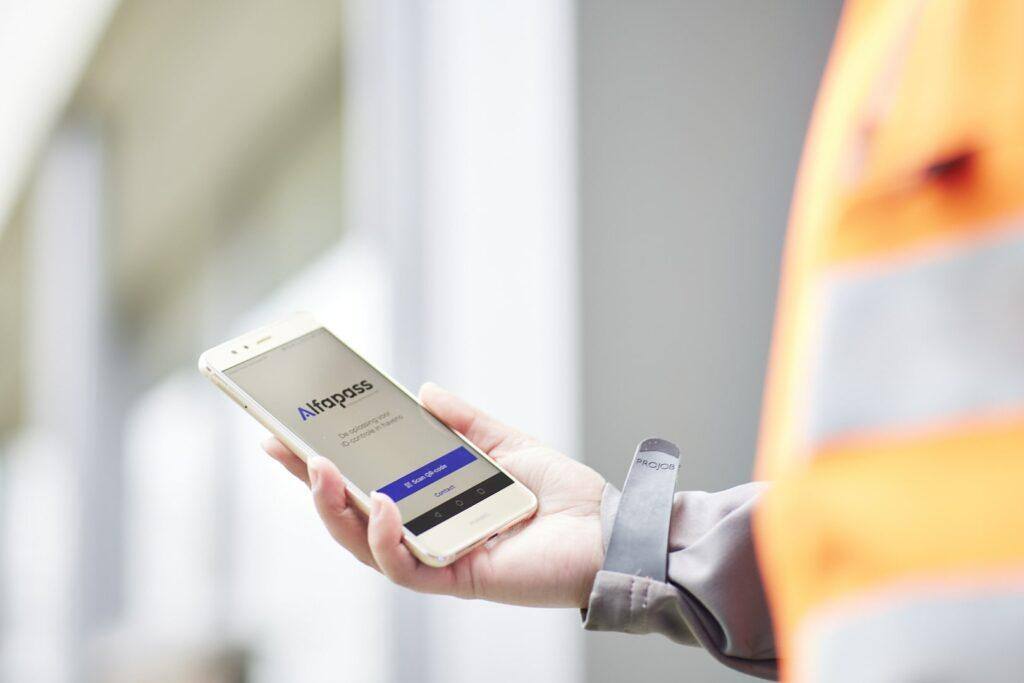 a man holding a smartphone with Alfapass app