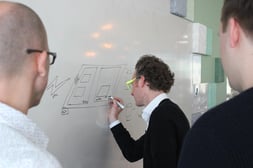 Teams die samen workflows bekijken tijdens een DevOps-coaching om de samenwerking en leveringssnelheid te verbeteren