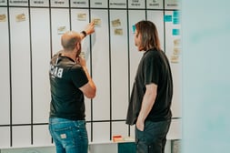 Teamleden bespreken taken op een bord tijdens een Agile coachingsessie om planning en samenwerking te verbeteren